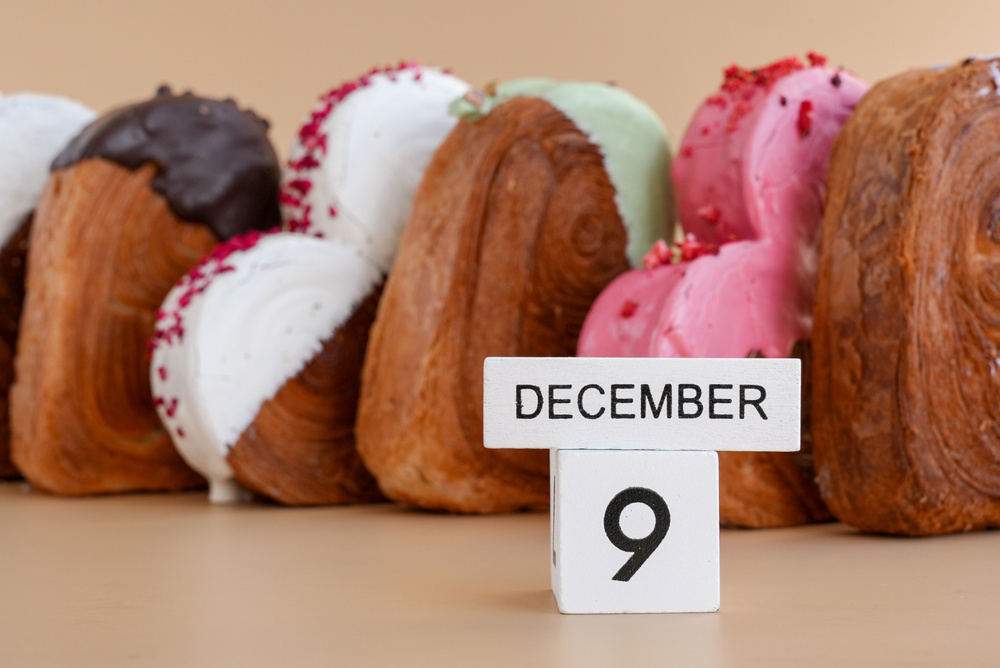 Pastry day 9 December wooden calendar cubes wishes greeting holiday card Heart shaped pastry croissant treat topped with colorful frosting galore. Food experimentation viral dessert creative baking trend