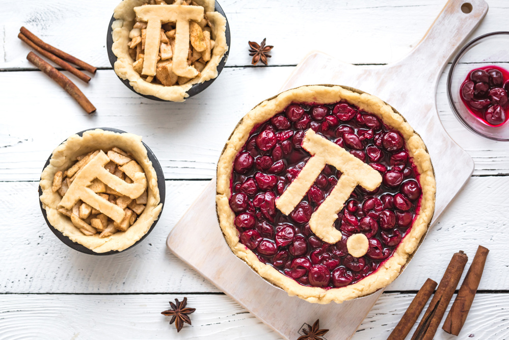 Pi Day Cherry and Apple Pies - making homemade traditional various Pies with Pi sign for March 14th holiday, on white wooden background, top view