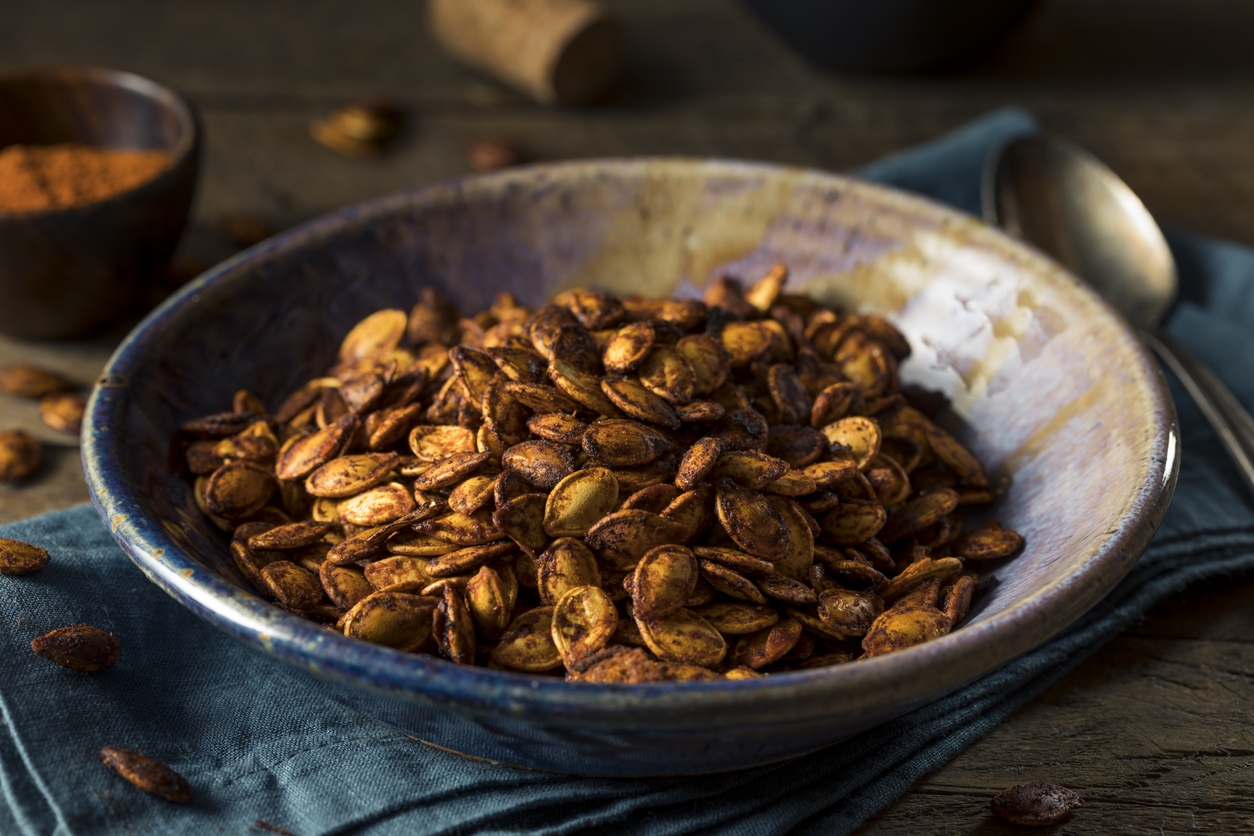 roasted seasoned pumpkin seeds in a dark-colored bowl