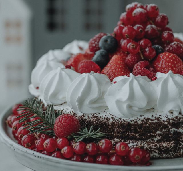 A cheesecake with berries and mint on a wooden plate