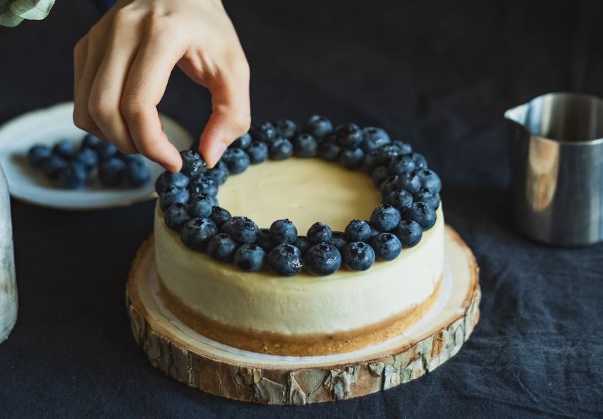 Person holding cake with white icing and blue icing