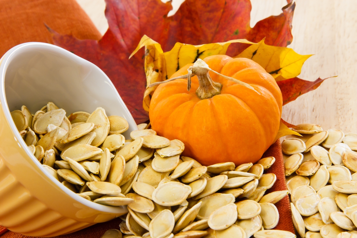 spilling pumpkin seeds with white husks in a ceramic yellow bowl, small size pumpkin