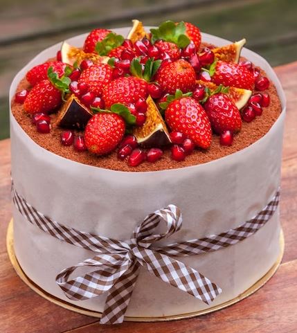 chocolate honey cake decorated with fresh strawberries, figs and pomegranate grains