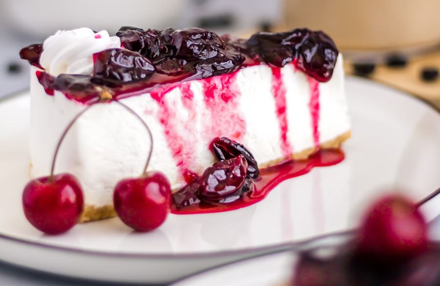 A slice of cheesecake with cherries and whipped cream